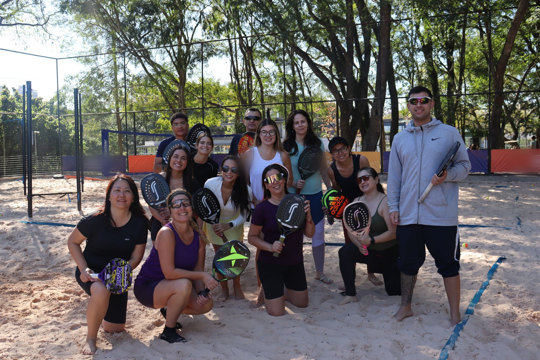 Grupo de praticantes de beach tennis reunido na quadra da Orla TotalPass